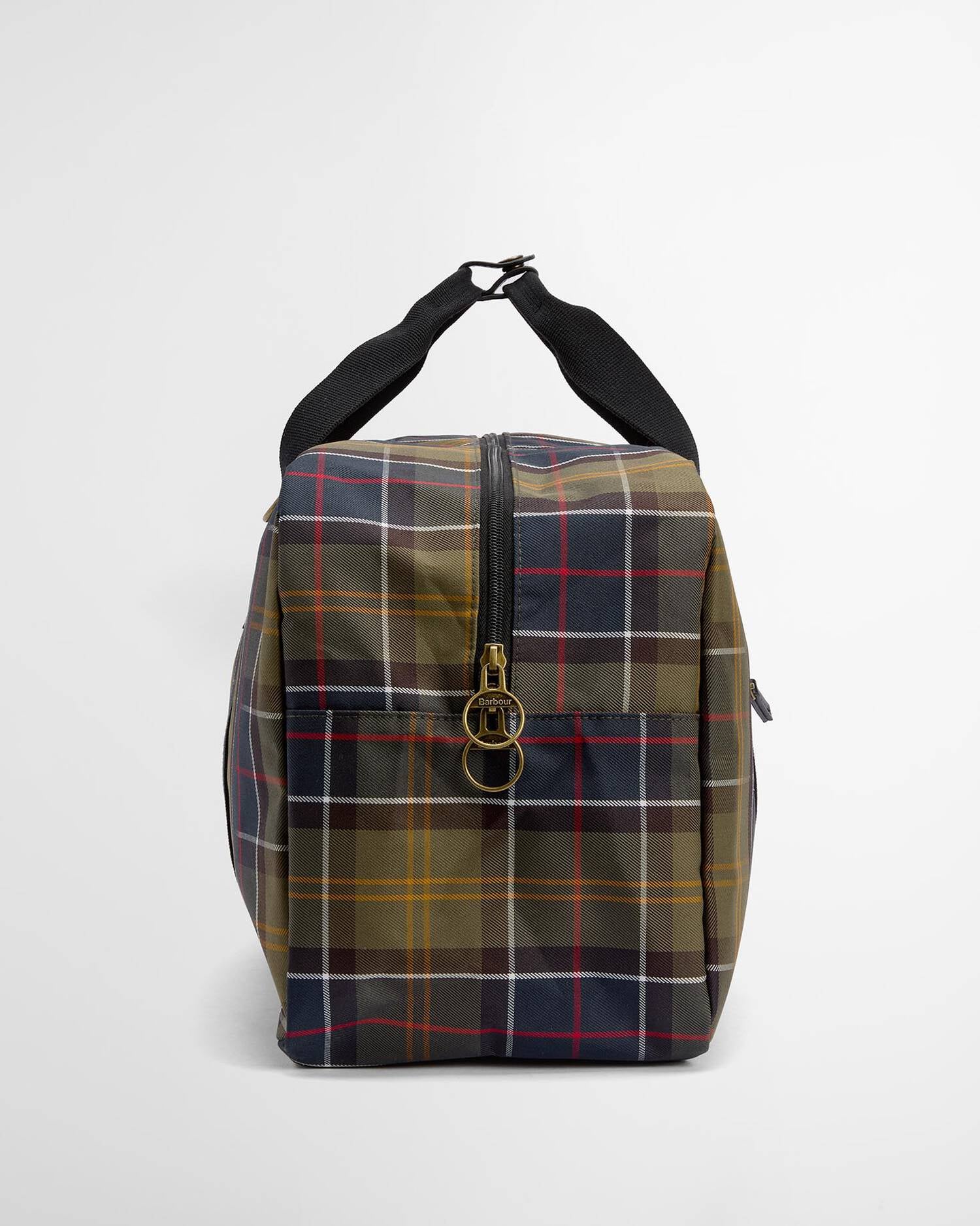 A square-shaped waxed canvas duffel bag featuring a classic tartan plaid pattern in olive green, navy blue, red, and yellow. It has a black top handle, a front zippered pocket with a gold-tone metal zipper pull, and a black shoulder strap, photographed on a clean white background.