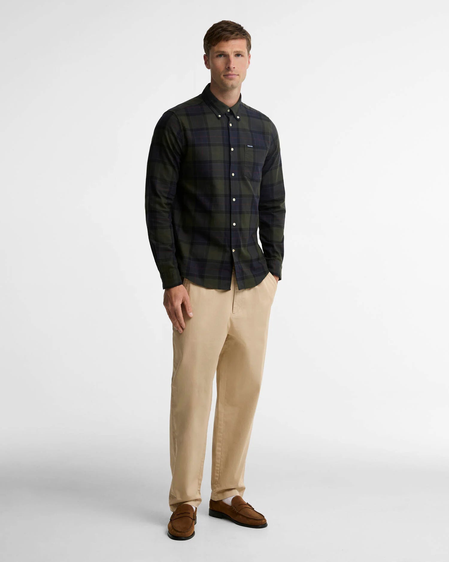 Man wearing a plaid shirt, beige pants, and brown shoes on a white background