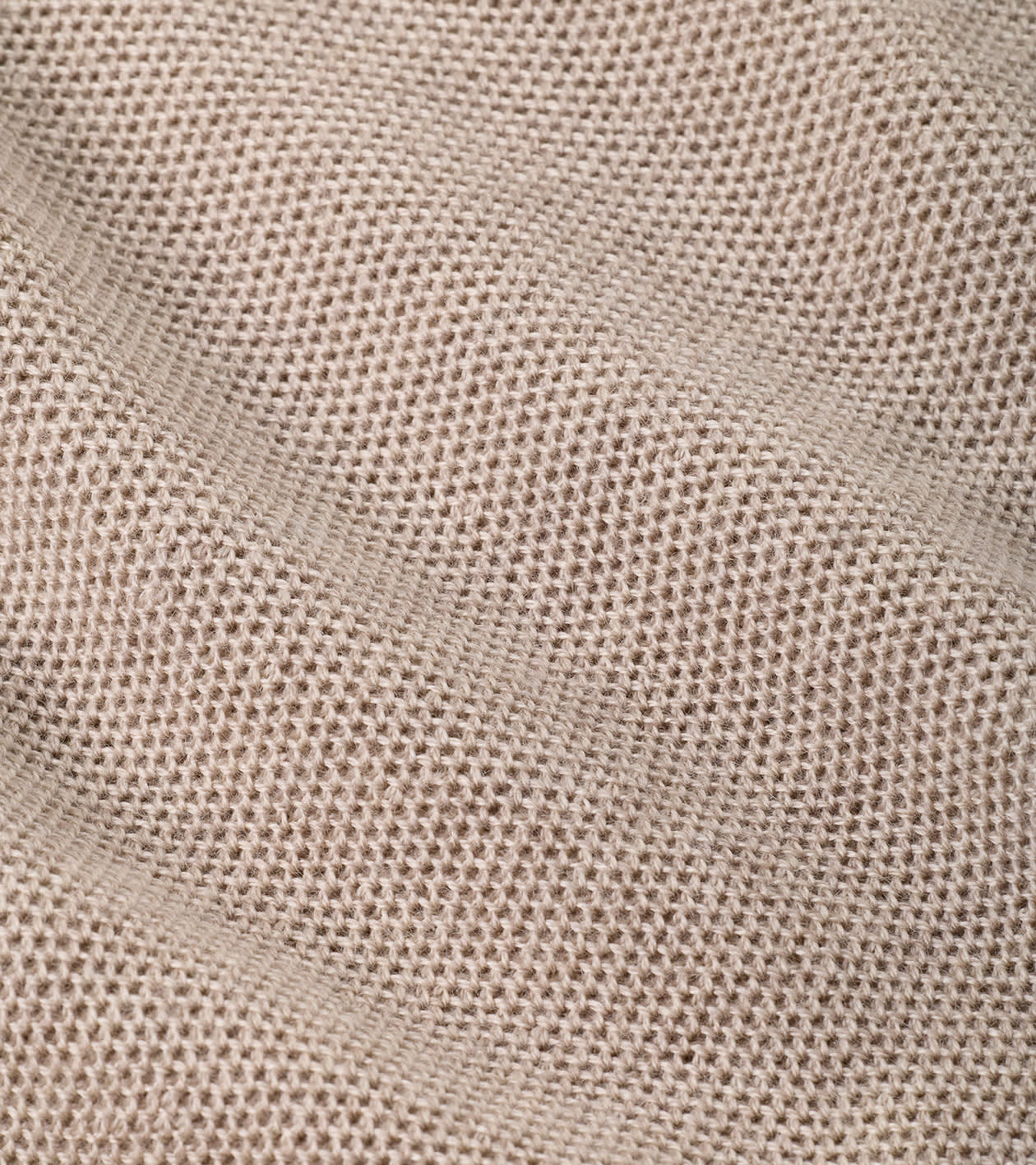 A close-up of a woven fabric texture in a light beige or oatmeal color, showing the detailed knit pattern and soft folds.
