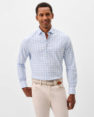 Man wearing a blue checkered shirt and beige pants on a light gray background