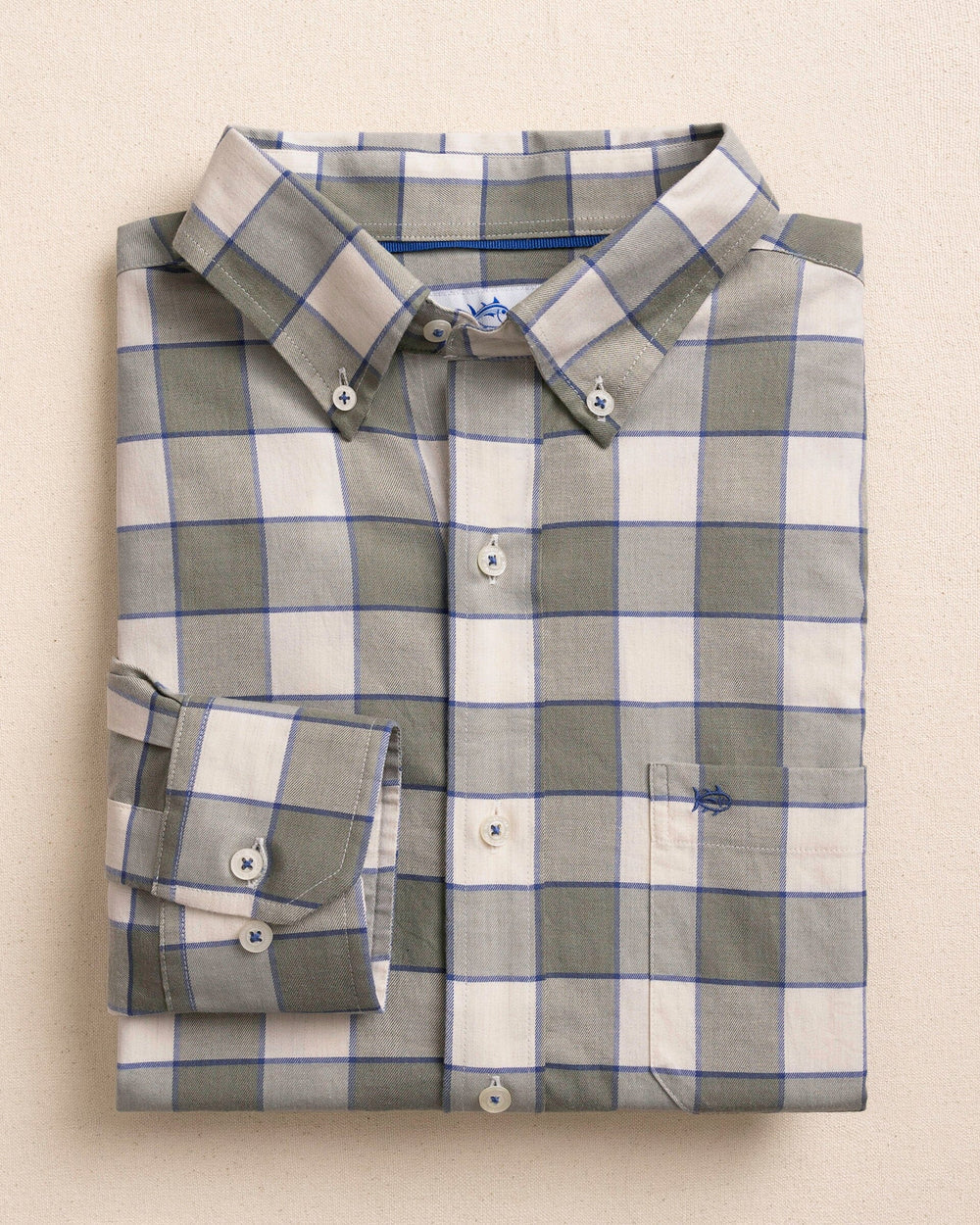 A folded long-sleeve button-down shirt with a gray, white, and blue windowpane plaid pattern, displayed on a neutral beige background.