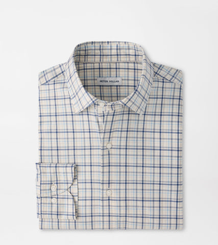 A Peter Millar long-sleeve dress shirt in a white base with a blue and light gray windowpane plaid pattern, neatly folded on a light gray background.