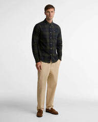 Man wearing a plaid shirt, beige pants, and brown shoes on a white background