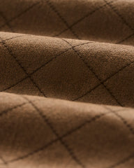 Close-up of a brown textured fabric with a diamond quilted pattern stitched in a darker brown thread.